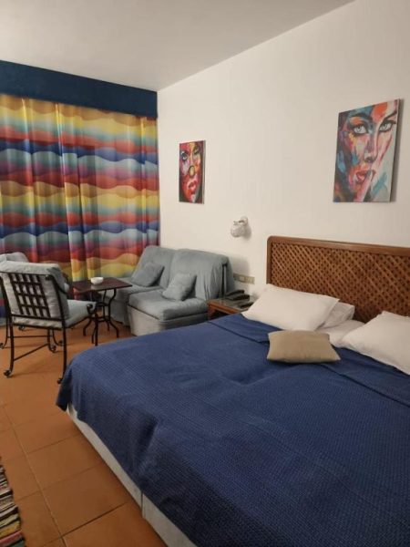Habitación doble con cama grande, sofá y decoración colorida en Domina Coral Bay Sea View Studio
