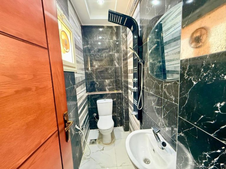Baño completo con ducha, inodoro y lavabo revestido de mármol negro en Winter House