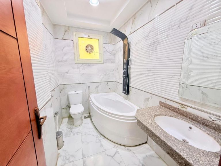 Baño completo con bañera de esquina, ducha, lavabo y suelo de mármol en Winter House
