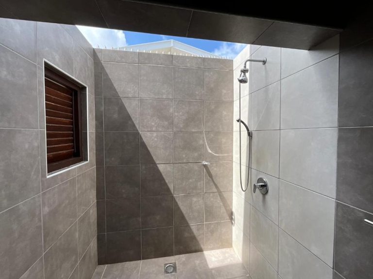Ducha exterior abierta con azulejos grises y luz natural en Bantopa Apartments
