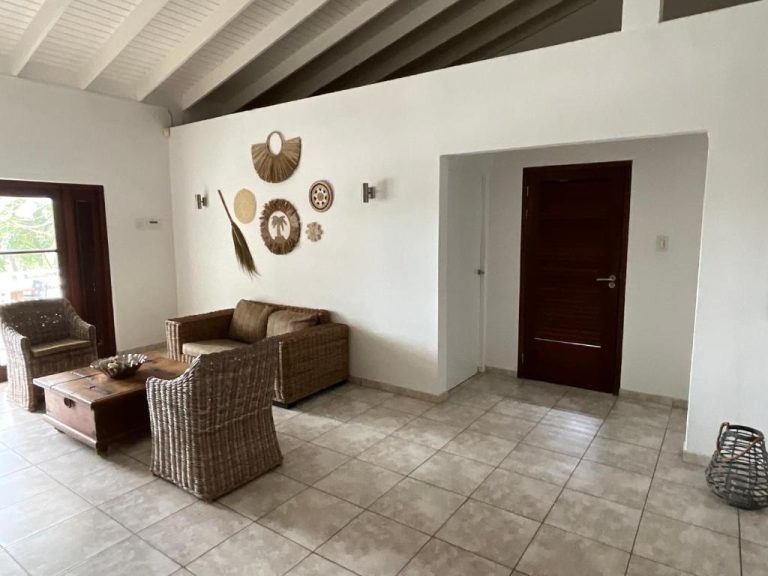 Sala de estar con sofás de ratán y decoración tropical en Bantopa Apartments Curazao