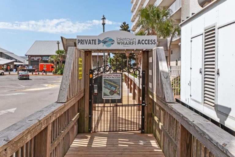 Acceso privado a la playa del resort Laketown Wharf con pasarela de madera y puerta exclusiva para huéspedes