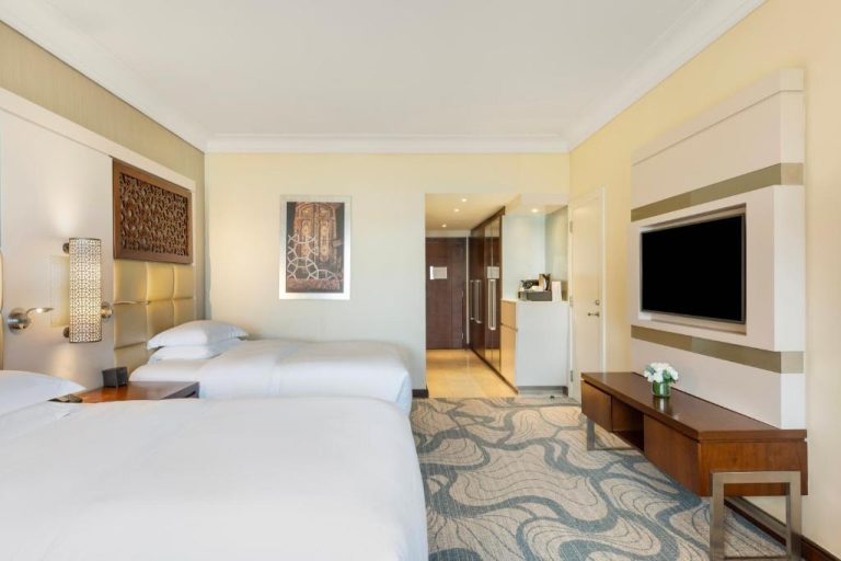Habitación twin de lujo con dos camas y televisor en InterContinental Doha Beach & Spa by IHG