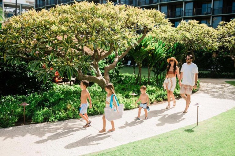 Familia con niños paseando por los jardines tropicales del OUTRIGGER Kāʻanapali Beach Resort en Maui