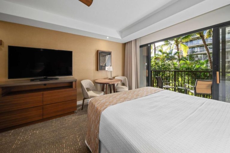 Habitación con cama king, TV y balcón con vistas a palmeras en OUTRIGGER Kāʻanapali Beach Resort Maui