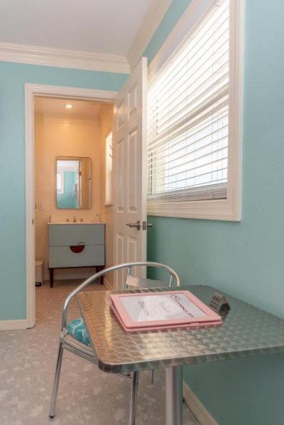 Habitación con escritorio metálico estilo retro y baño privado en el Flamingo Inn