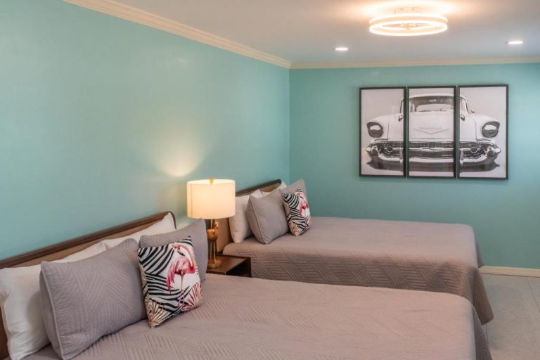 Habitación doble con dos camas y paredes turquesa en el Flamingo Inn, decorada con cojines tropicales
