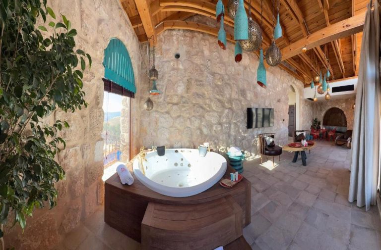 Jacuzzi privado en suite de piedra con techo de madera y decoración oriental en Tal Rumman Boutique Hotel
