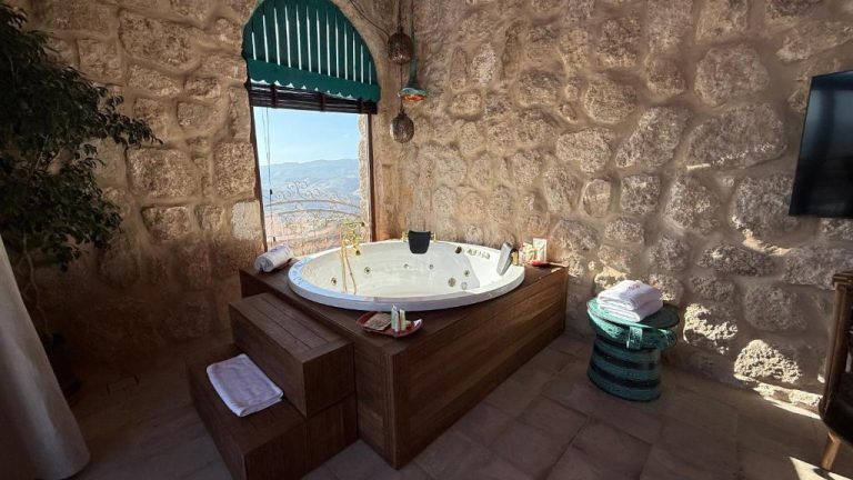 Jacuzzi privado con vistas a las montañas en habitación de piedra del Tal Rumman Boutique Hotel
