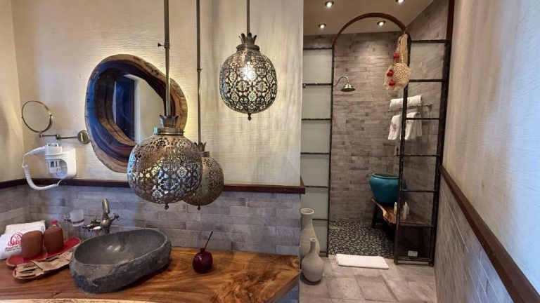 Baño artesanal con lavabo de piedra, lámparas marroquíes y ducha de obra en Tal Rumman Boutique Hotel