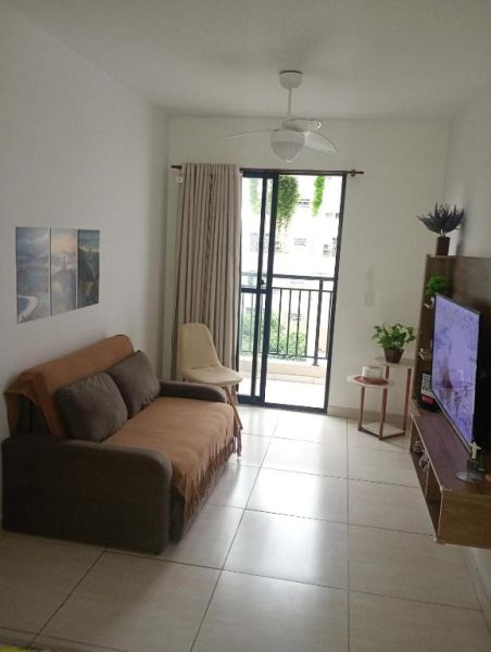 Sala de estar con sofá marrón, televisor y balcón con vista exterior en Hospedagem para grupos