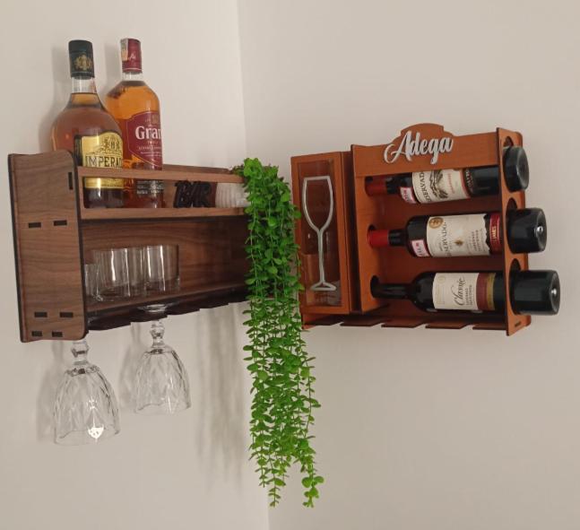 Adega de parede com garrafas de vinho e whisky, taças e suporte decorativo em madeira na Hospedagem para Grupos