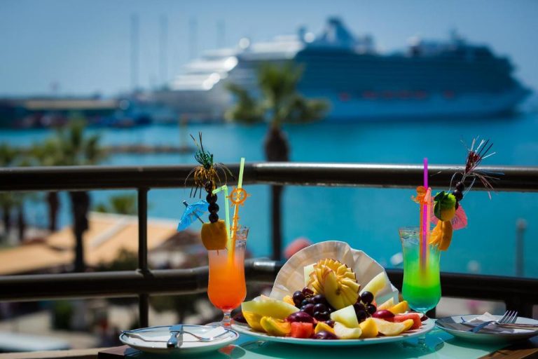 Cócteles tropicales y bandeja de frutas en la terraza del Derici Hotel con vistas al mar y crucero