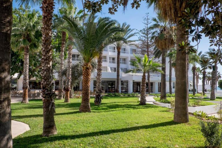 Jardines tropicales con palmeras frente al edificio principal del Hotel Bel Azur Thalasso & Bungalows
