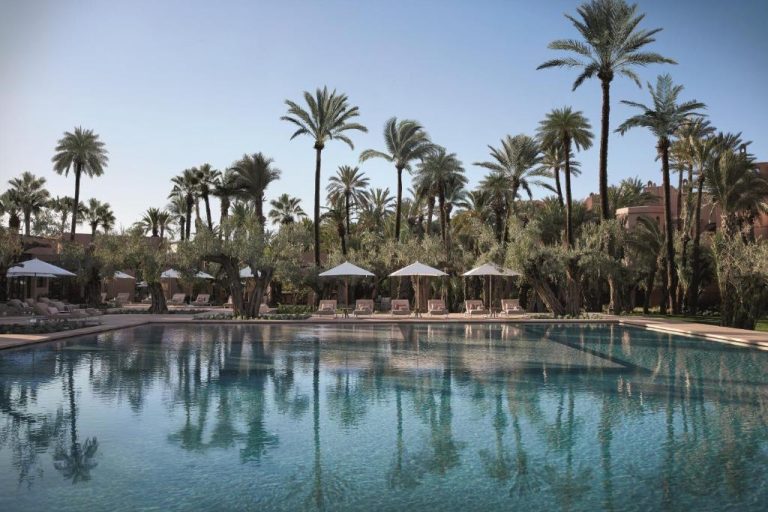 Piscina exterior rodeada de palmeras y tumbonas del Royal Mansour Marrakech