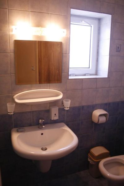 Baño completo con lavabo, espejo de madera y ventana del Mariam Hotel