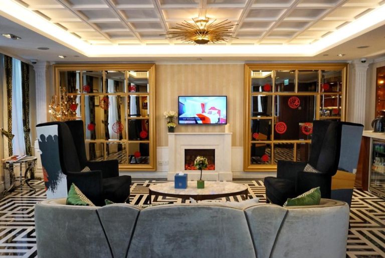 Elegante salón con chimenea, sofás y televisor del Hotel Madera Hollywood en Los Ángeles