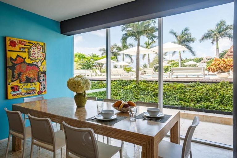 Comedor luminoso con vista a la piscina y jardines tropicales en Magia Beachside Condo