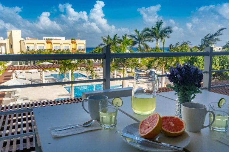 Desayuno en terraza con vista a la piscina y palmeras en Magia Beachside Condo