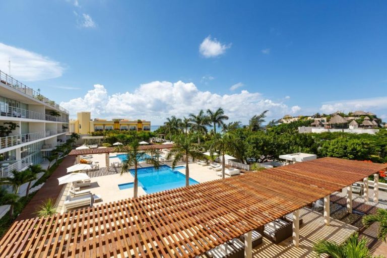 Piscina exterior con terraza de madera y tumbonas del Magia Beachside Condo con vistas al mar