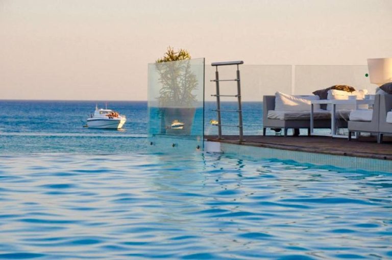 Piscina infinita con vistas al mar y zona lounge exterior del hotel The Sindbad
