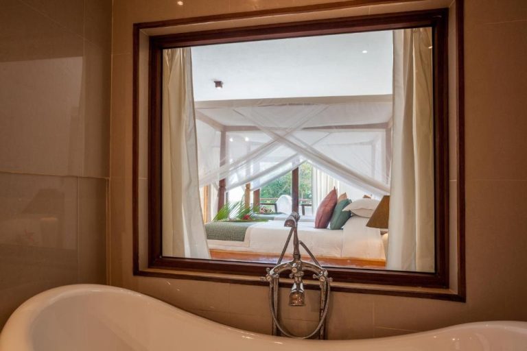 Bañera exenta de lujo con vistas al dormitorio con dosel en Ocean Village Club Adults Only