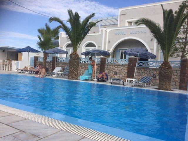 Piscina exterior con tumbonas y palmeras tropicales del Alkyon Hotel en Grecia