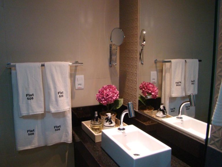 Baño moderno con lavabo blanco, toallas personalizadas y flores rosas en el Flat 508 Recife