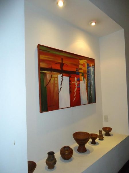 Pintura abstracta y colección de cerámicas artesanales decorando el pasillo del Hotel Casa del Sol