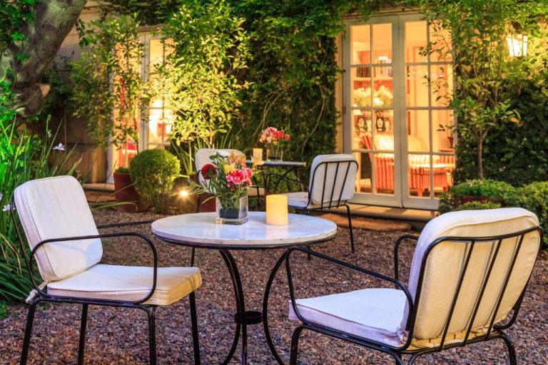 Terraza jardín con mesas y sillas de hierro forjado iluminadas al atardecer en Hotel Boutique Le Reve