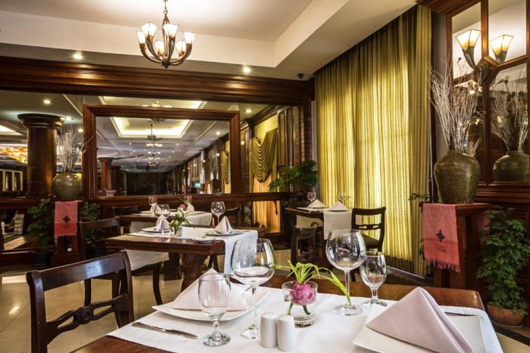 Elegante restaurante interior del Prince Angkor Hotel & Spa con mesas vestidas y decoración en madera oscura