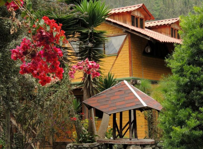 Cabaña de madera con jardín tropical y buganvilias rojas en el Hotel La Casta