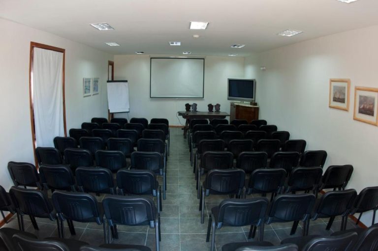 Sala de reuniones y conferencias del Hotel Papiros con sillas, pantalla de proyección y televisión