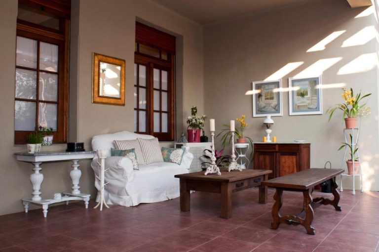 Salón con sofá blanco y mesas de madera en estilo rústico del Hotel Papiros con luz natural