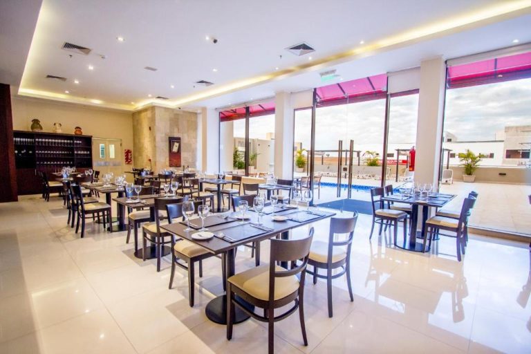 Salón comedor del Carnaval Hotel Casino con mesas elegantes, copas de cristal y vista a la terraza