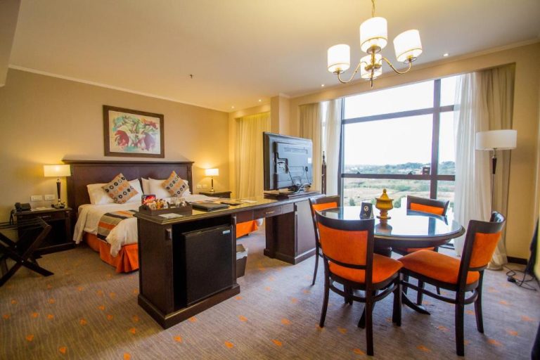 Suite del Carnaval Hotel Casino con cama, mesa de comedor, televisor y amplia ventana con vistas panorámicas