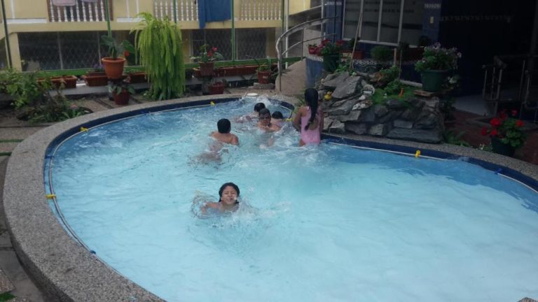 Niños disfrutando de la piscina exterior del Hotel Fuentes del Volcán rodeada de jardines y plantas