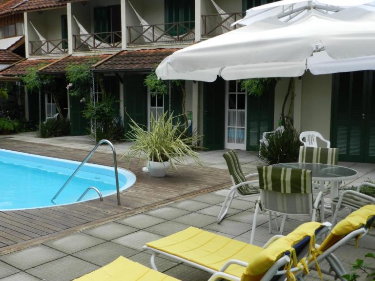 Piscina exterior con tumbonas y sombrilla blanca en Residencial Pontal do Jurerê, Brasil