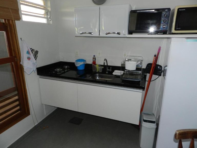 Cocina equipada con encimera negra, microondas y horno en Residencial Pontal do Jurerê