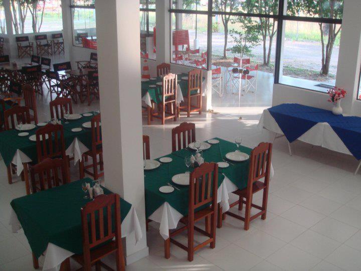 Comedor interior del Hotel Ruta del Sol con mesas vestidas en verde y sillas de madera junto a ventanales