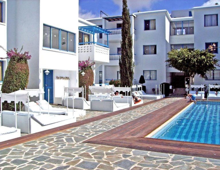 Piscina exterior con tumbonas blancas y zona de relax del Tasmaria Aparthotel en Chipre
