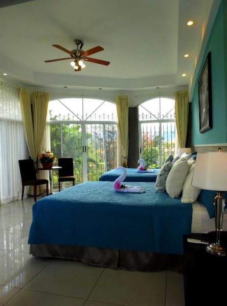 Habitación doble con camas azules y vista al jardín en Alameda Cariari Boutique Hotel