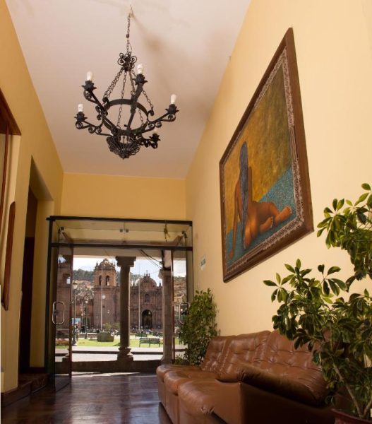 Lobby del Hotel Katari Plaza Cusco El Virrey con sofá de cuero, lámpara colonial y vista a la Plaza de Armas