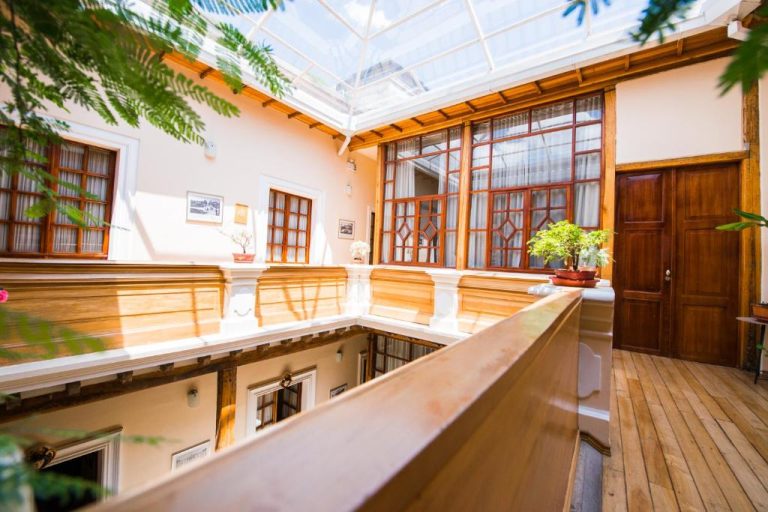 Patio interior con galería acristalada y balcón de madera en Casa El Edén