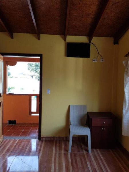 Habitación con televisor, escritorio y silla en Hotel Fuentes del Volcán con acceso a terraza exterior