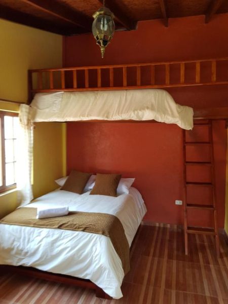 Habitación con cama doble y litera de madera en Hotel Fuentes del Volcán, decoración rústica colonial