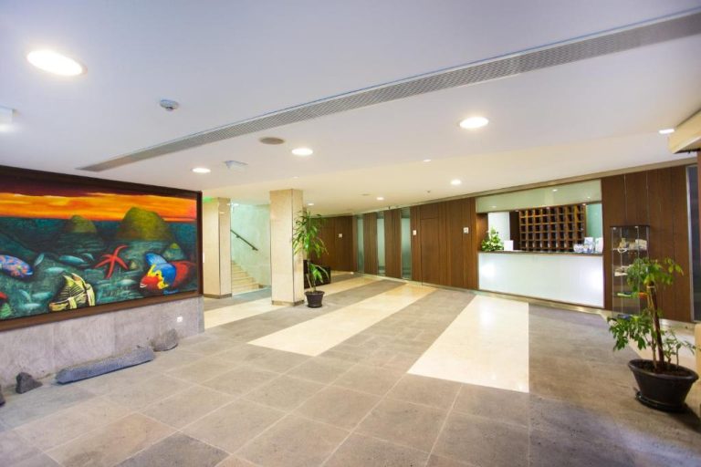 Amplio lobby con recepción y mural marino colorido en el Antillia Hotel
