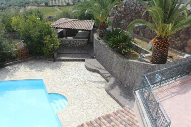 Piscina exterior con terraza de piedra natural y palmeras en el Hotel Le Tre Rose