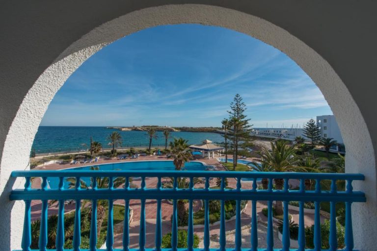 Vista desde balcón con arco blanco del Regency Hotel & Spa con piscina exterior y mar al fondo