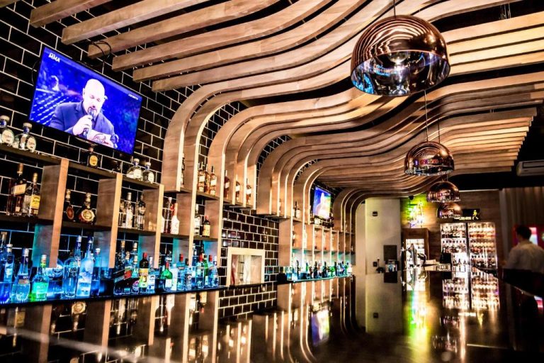 Bar lounge moderno con amplia selección de licores y decoración ondulada en 7 Saltos Resort